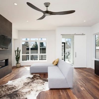 Ventilateur plafond silencieux avec télécommande installé dans un salon moderne, au-dessus d’un canapé gris et d’un parquet en bois.