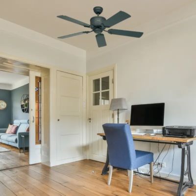 Ventilateur déstratificateur monté au plafond au-dessus d’un bureau avec chaise et ordinateur dans un intérieur domestique.