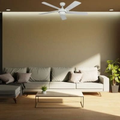 Ventilateur de plafond blanc installé au-dessus d’un canapé dans un salon lumineux.