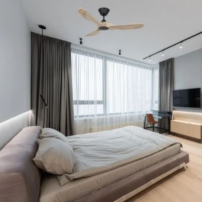 Ventilateur de plafond avec trois pales en bois dans une chambre lumineuse.